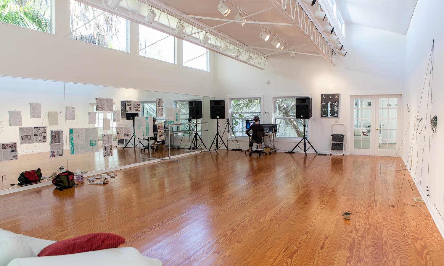 A white studio with a wood floor and a mirrored wall